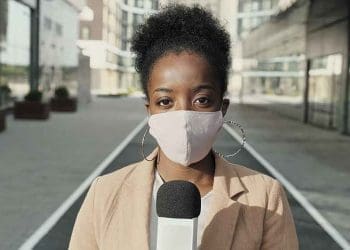 How to report the science of COVID-19 course. Image of African female reporter in mask holding microphone