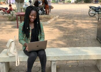 Young woman sitting on a bench, working on a laptop, exploring tips for journalists on structuring a science story.