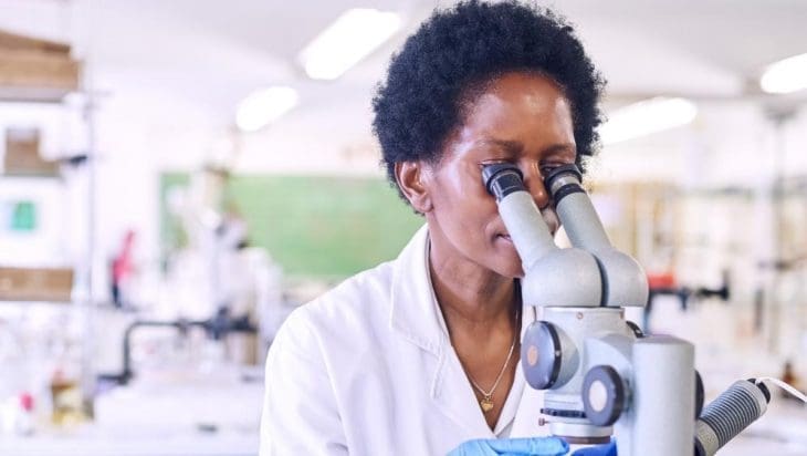 Science communication award story image: Female African scientists in a laboratory looking through a microscope