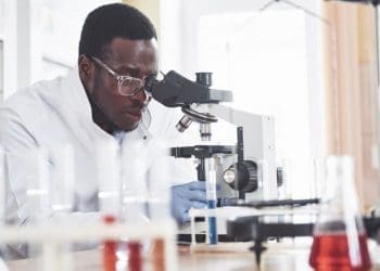African scientist looking through a microscope