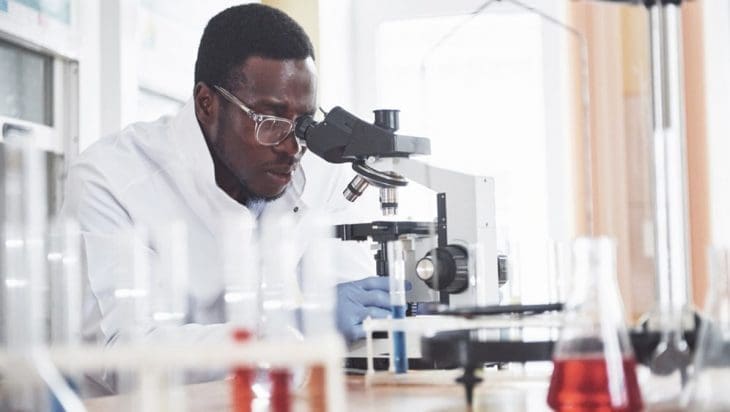 African scientist looking through a microscope