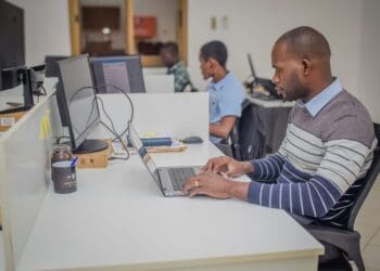 A man at a desk, focused on his laptop, working on a policy brief for researchers in Africa.